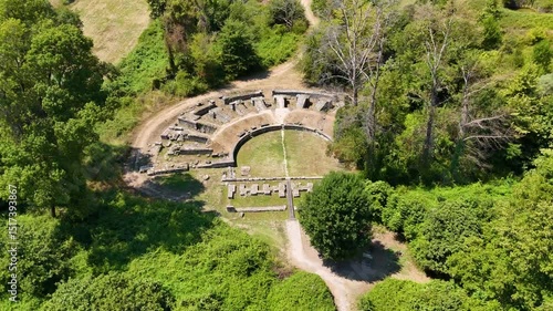 Aerial view of ancient amphitheater ruins of Dion, Greece surrounded by lush greenery.