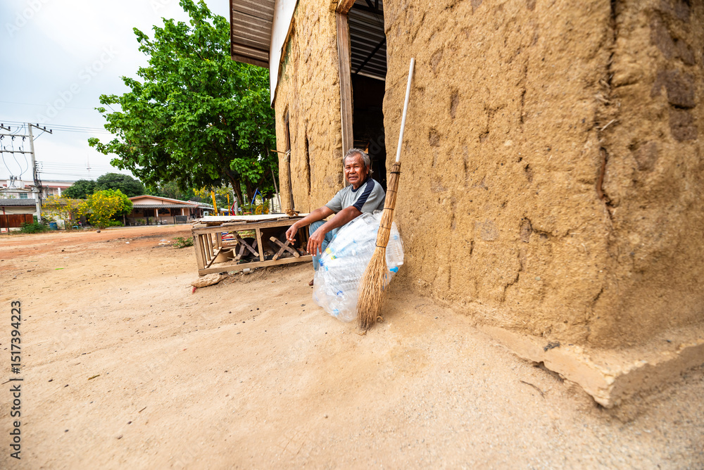 Elderly Thai man smiling in front of an abandoned house with collected Elderly Thai man smiling in front of an abandoned house with collected