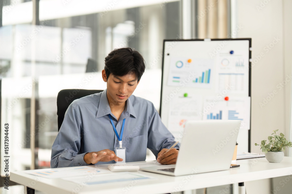 Obraz premium Productive Workspace. Young man using smartphone while working on laptop.