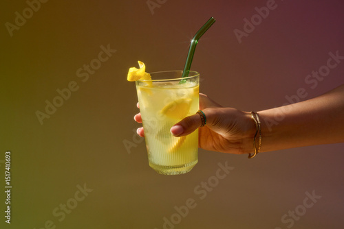 A hand holds a refreshing glass of lemonade, perfect for summer