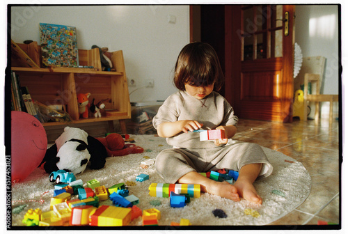 Child playing with building blocks on rug in toy-filled room