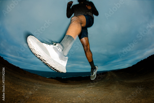 Flash-lit wide shot of a trail runner taking a long stride