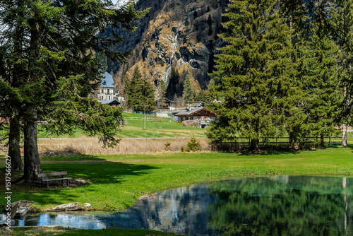 Wallpaper Mural Alpine lake Gover surrounded by green trees as a mountain with a waterfall in the background in Gressoney Saint Jean, Italy. Torontodigital.ca