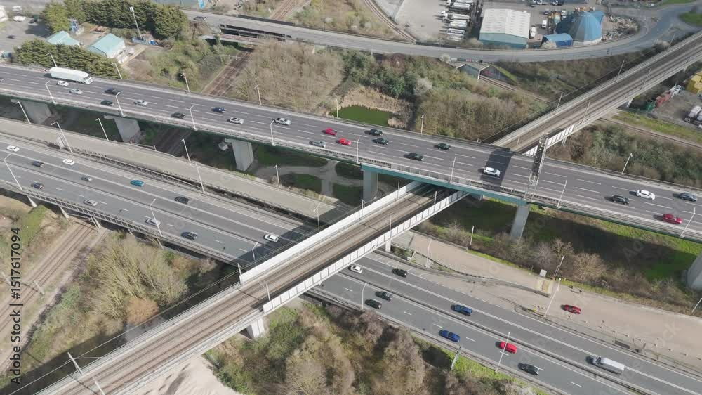Dynamic aerial over multilane A282 interchange as streams of cars and lorries traverse stacked bridges and ramps through Thames-side transport hub Dynamic aerial over multilane A282 interchange as streams of cars and lorries traverse stacked bridges and ramps through Thames-side transport hub