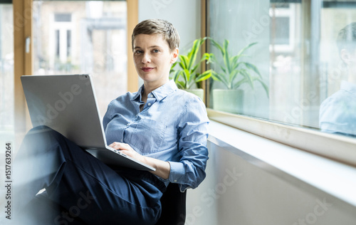 Businesswoman working on a laptop in a modern office setting