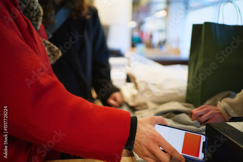 Wallpaper Mural Woman scanning through smart phone for paying at checkout counter in clothing store Torontodigital.ca
