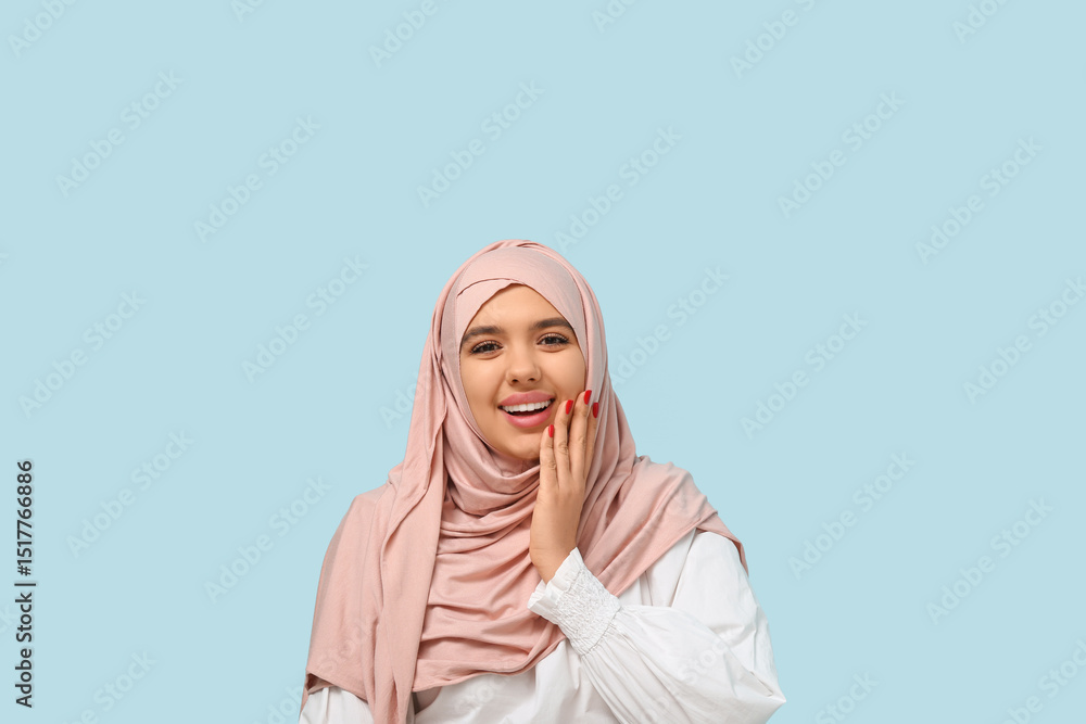 Fototapeta premium Happy young Muslim woman in hijab on blue background