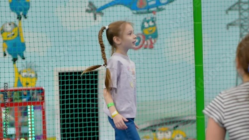 A little girl jumps on a trampoline at a children's entertainment playground, smiles, a place for text. Selective attention.