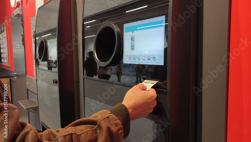 Warsaw, Poland - May 31, 2025: Close up of man hand getting coupon from recycling machine for inserted bottles