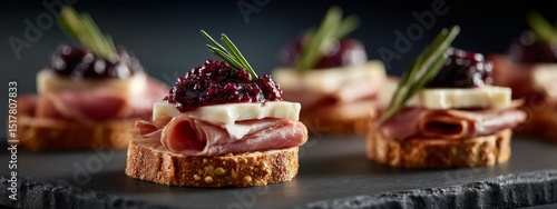 Small charcuterie platter featuring sliced ham cheese and blackberry jam on rustic bread slices arranged on wooden serving board with decorative presentation