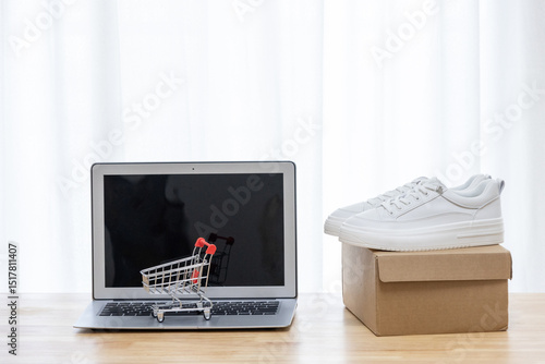 Laptop, shopping cart, and delivery package on a desk