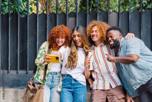 Fotografija Vibrant young friends hugging, laughing while snapping smartphone selfie against