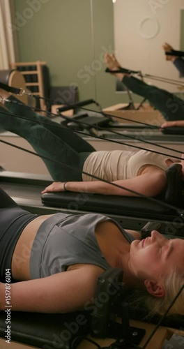 Group of Woman Doing Pilates Exercise on Pilates Reformer for the Chest and Back Muscles, Focusing on Flexibility, Strength, and Control with Determination. Instructor Helping