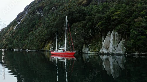 Wallpaper Mural Red sailboat drifts still in glassy fjord waters with symmetrical forest reflections, medium orbit aerial Torontodigital.ca