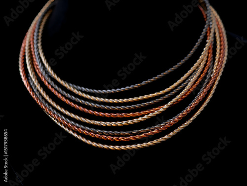 Elegant twisted metal strand necklace in copper, bronze, gold, and silver on a black background