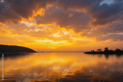 beautiful sunset over a body of water with a bridge in the background