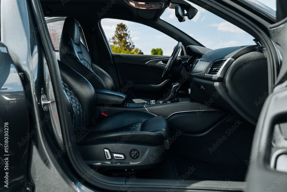 Fototapeta premium Sports car interior. Black premium leather, bucket seats, steering wheel, buttons, console with gears and widescreen. Luxury car interior design. Marketing, advertising or press articles.
