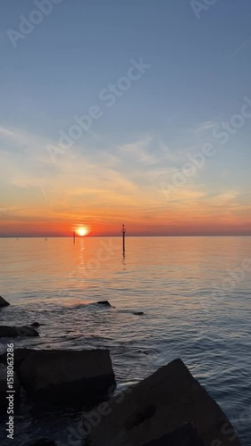 Sunrise light over gentle waves and coastal rocks at Barceloneta Beach