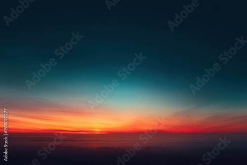 Vibrant sunset hues paint a low-hanging, hazy sky, transitioning from deep teal to fiery orange and red, with a subtle glow on the horizon