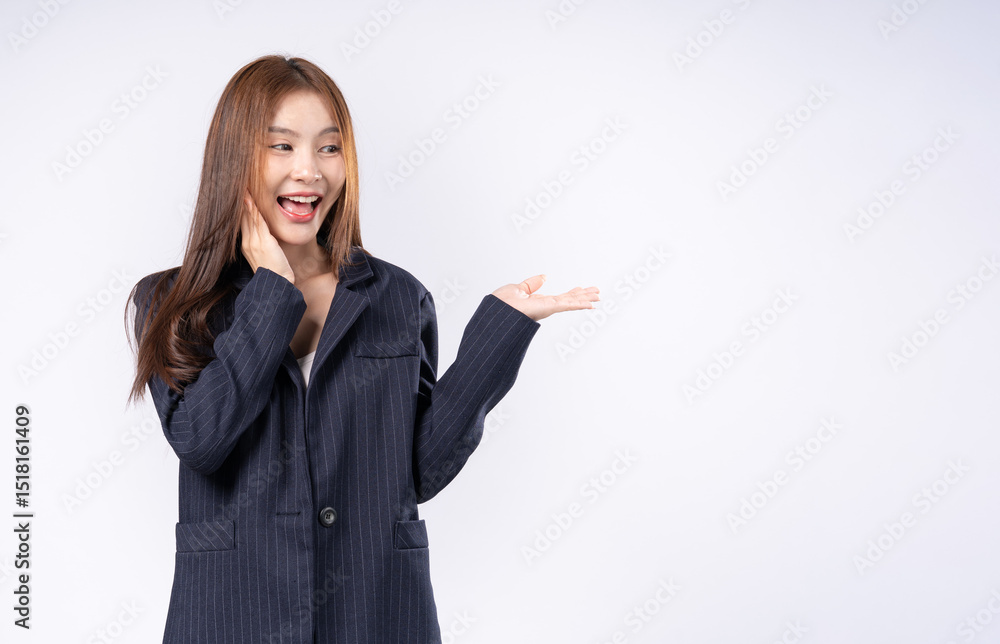 Beautiful Asian woman in suit raising one arm with palm up gesture showing something in hand face excited and smiling portrait in studio white background Beautiful Asian woman in suit raising one arm with palm up gesture showing something in hand face excited and smiling portrait in studio white background