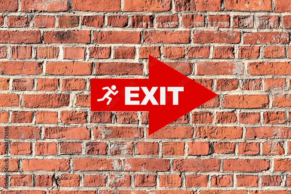 Fototapeta premium Red exit sign pointing to the right on brick wall