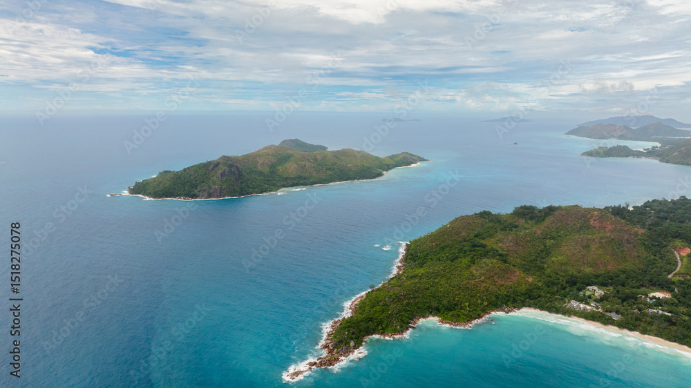 Fototapeta premium Aerial drone of lush green islands surrounded by vibrant turquoise waters, fading into the endless horizon. Praslin, Seychelles.