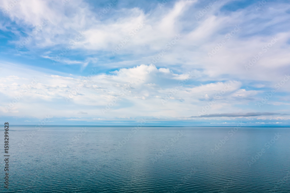 Obraz premium Panoramic view of Lake Issyk-Kul with clear water and blue sky with clouds in Kyrgyzstan. Nature landscape of Issyk-Kul in Kyrgyz Republic with Tien-Shan mountains