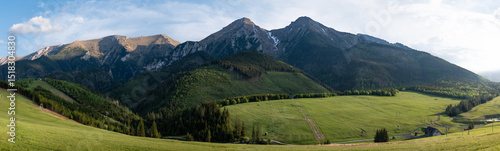 Obraz na płótnie Panoramic view of High Tatras peaks including Havran and Ždiarska vidla above green meadows and forest near Ždiar, Slovakia, with ski lift structures visible in the landscape