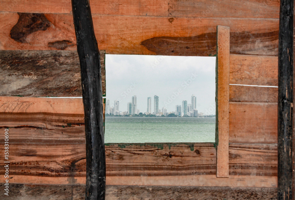 Fototapeta premium View of the sea and the buildings of the Bocagrande neighborhood of Cartagena, through the wooden window of a house on the island of Tierrabomba
