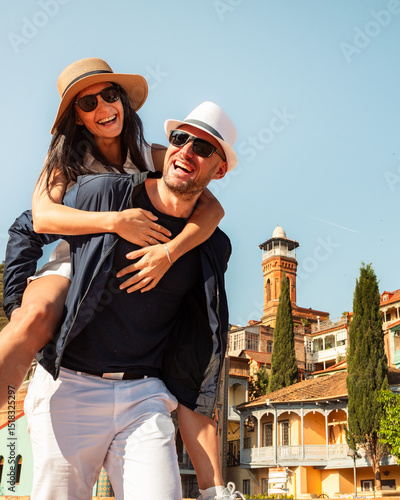 Romantic Couple tourists having fun walking Tbilisi city streets on holiday. Happy friends laughing together on vacation - People and holidays concept. Man carrying woman enjoy time together travels