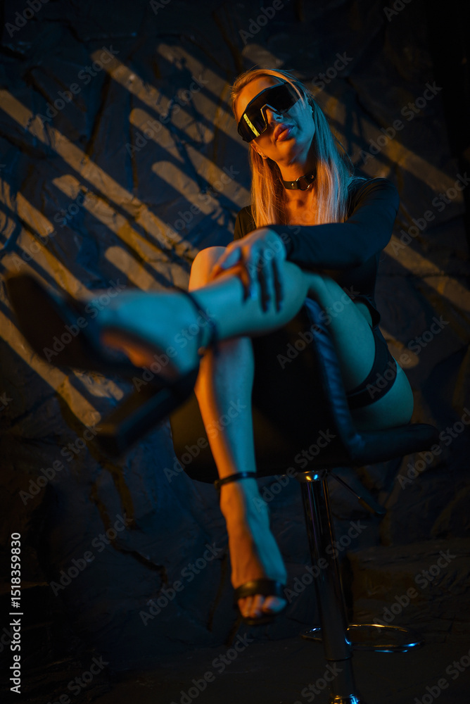 Fototapeta premium Beautiful woman posing as secret agent in black bodysuit holding weapon on dark background..
