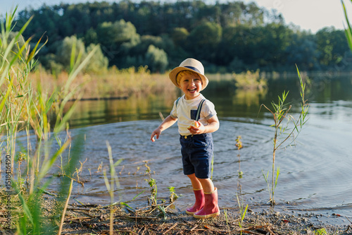 Obraz na plátně Toddler walking through lake shallows in rubber boots
