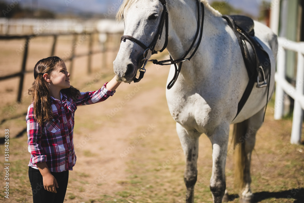 Obraz premium Girl standing beside light gray horse in ranch paddock petting muzzle near wooden rail fence