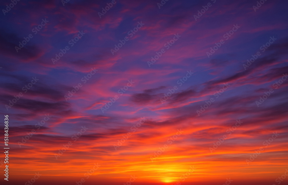 Fototapeta premium Fiery sunset sky with deep orange, purple and indigo clouds