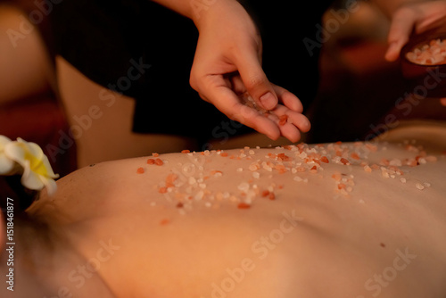 Couple customer having exfoliation treatment in luxury spa salon with warmth candle light ambient. Salt scrub beauty treatment in Health spa body scrub. Quiescent