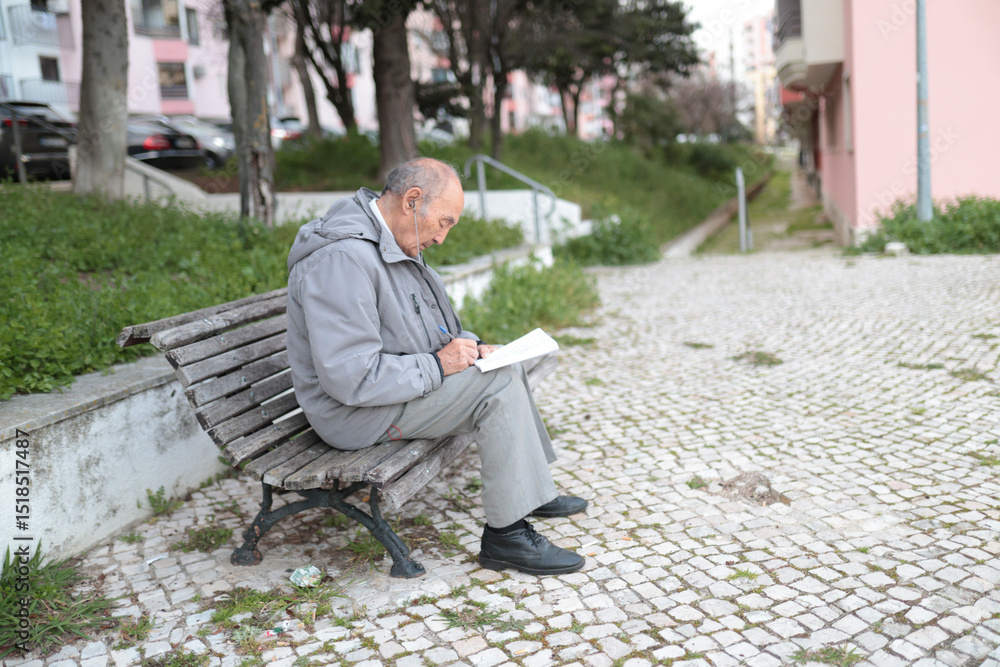 Fototapeta premium Senior man writing on paper while sitting on bench outdoors