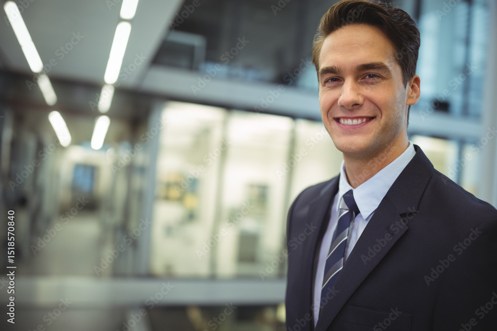 Fototapeta premium Man standing in office hallway wearing suit jacket and striped tie under linear lights, copy space