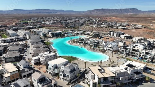 Drone modern villas surround a bright turquoise man-made lagoon, with palm trees and walkways