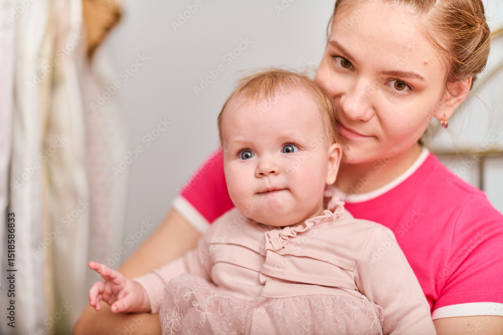 Young mother with light brown hair, holding baby girl. Woman wears pink top, baby in light dress. Warm emotions, indoor environment, bright lighting Young mother with light brown hair, holding baby girl. Woman wears pink top, baby in light dress. Warm emotions, indoor environment, bright lighting
