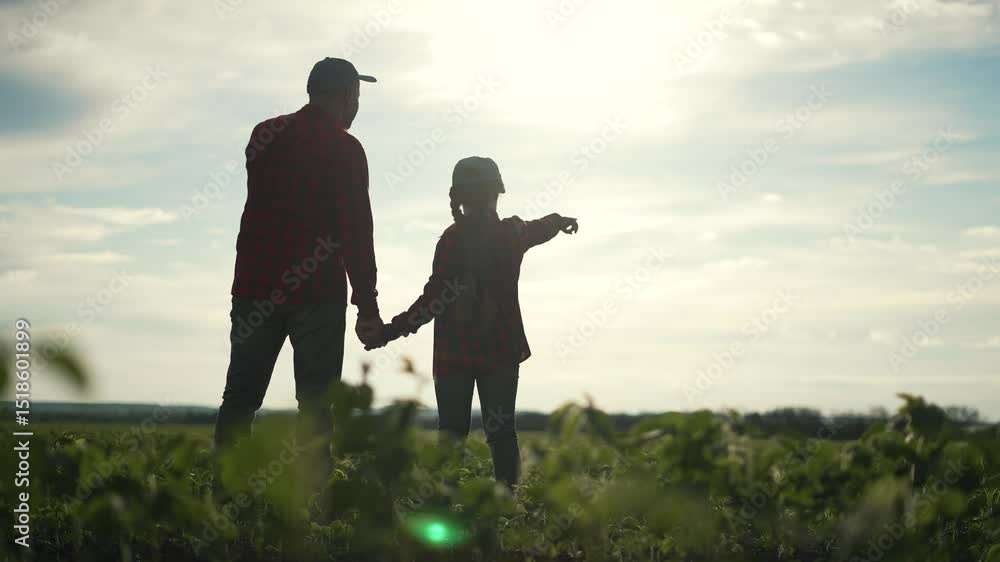 Farmer family in soybean field pointing at horizon. Father and daughter bonding in nature. Farmer teaches child about agriculture. Happy family farmer concept. Father and daughter in soybean field. Farmer family in soybean field pointing at horizon. Father and daughter bonding in nature. Farmer teaches child about agriculture. Happy family farmer concept. Father and daughter in soybean field.