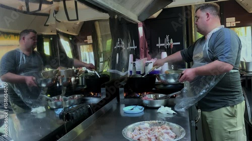 A chef prepares food in a food truck. A man is cooking in the kitchen.