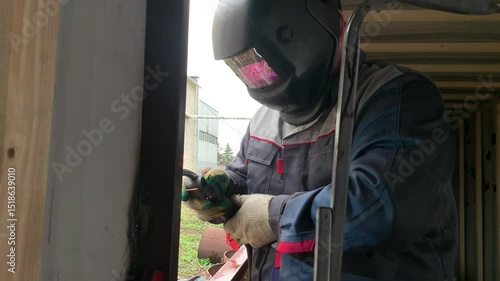 The welder works with a welding machine. A builder uses a welding machine to make a window frame.