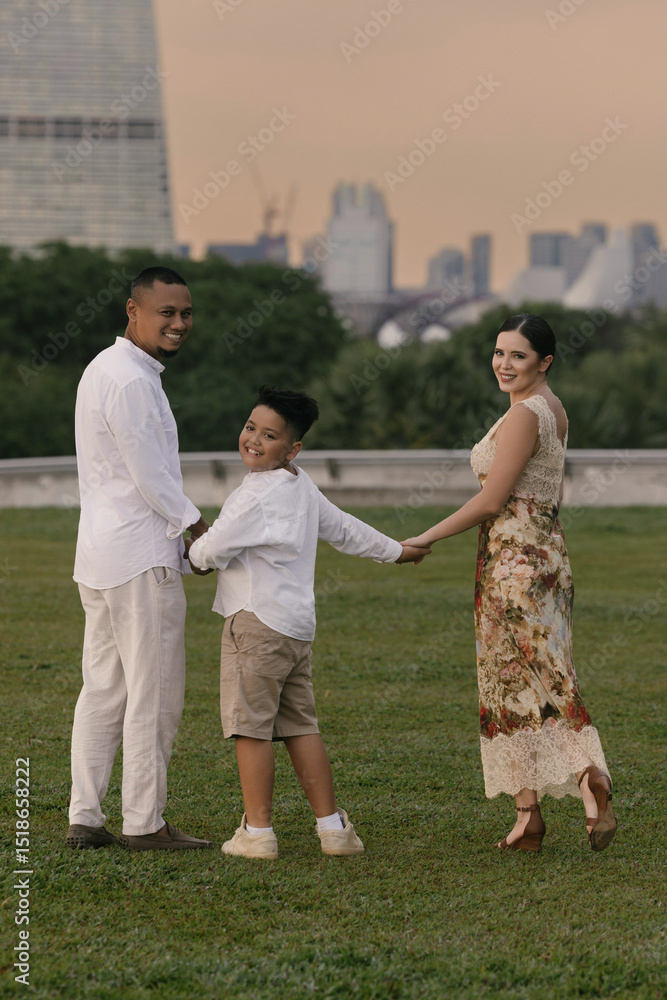 Obraz premium Elegant international family in Singapore. Asian father, Eastern European mother, and their child smiling near Marina Bay Sands. Diverse background and warm, joyful family moment outdoors