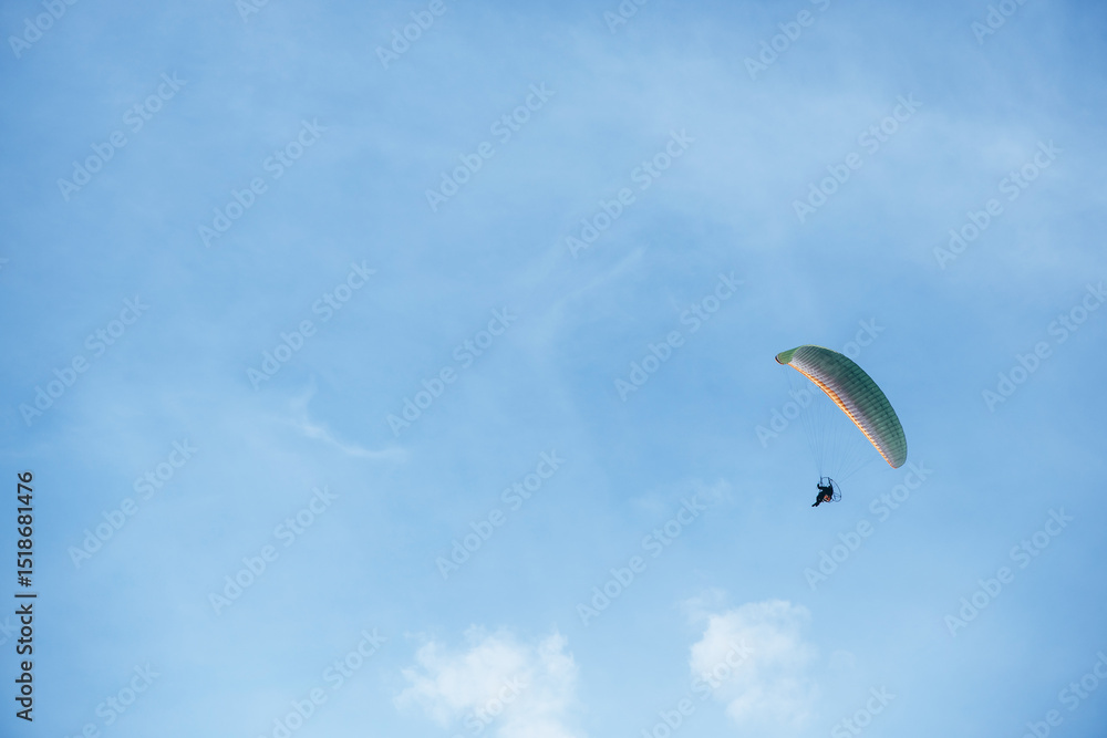 Paraglider flying high in the clear blue sky, extreme aerial sport symbolizing freedom, adventure, and outdoor recreation in natural open space Paraglider flying high in the clear blue sky, extreme aerial sport symbolizing freedom, adventure, and outdoor recreation in natural open space