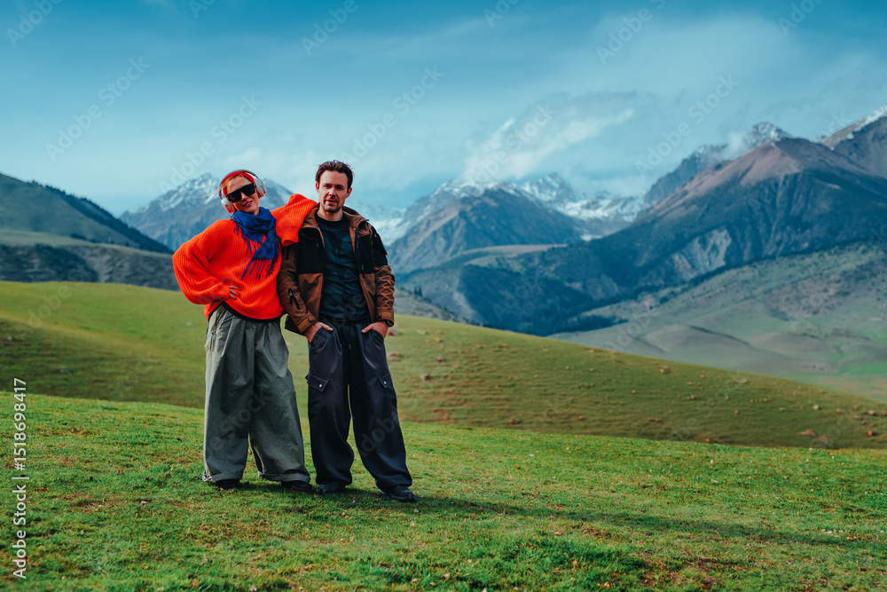 Man and woman tourists standing in the mountains on green meadow Man and woman tourists standing in the mountains on green meadow