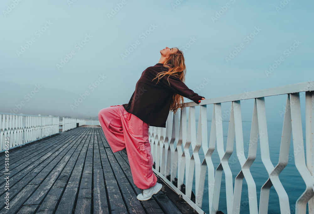 Young beautiful woman posing on pier on lake shore Young beautiful woman posing on pier on lake shore