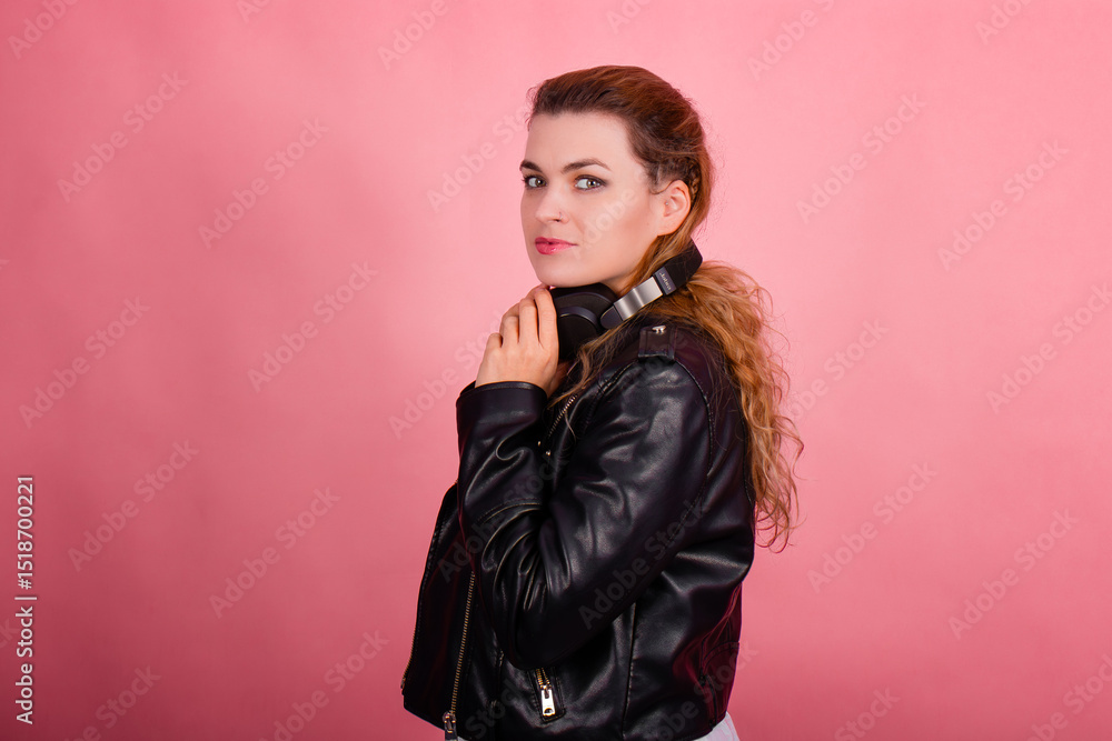 Fototapeta premium Woman with headphones, listening to music, fashion model in studio posing, music genre, smiling, rock, metal music
