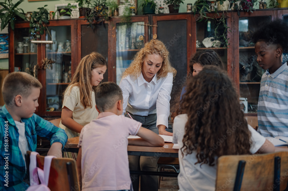Obraz premium Teacher helping diverse group of elementary school students studying together