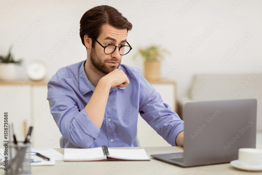 Surpirsed Business Guy In Eyewear Looking At Laptop Having Computer Problem Sitting At Desk In Modern Office. Issue With Internet Connection Concept. Selective Focus Surpirsed Business Guy In Eyewear Looking At Laptop Having Computer Problem Sitting At Desk In Modern Office. Issue With Internet Connection Concept. Selective Focus