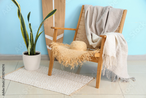 Cozy beach house interior with wooden chair, straw hat, blanket, potted plant...
